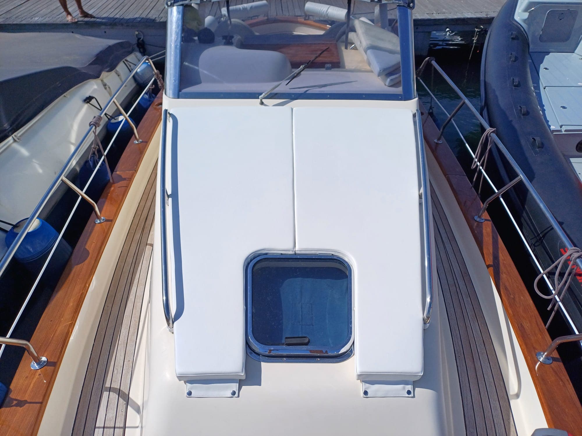 Cuscineria bianca prendisole su motoscafo in teak, vista dall’alto